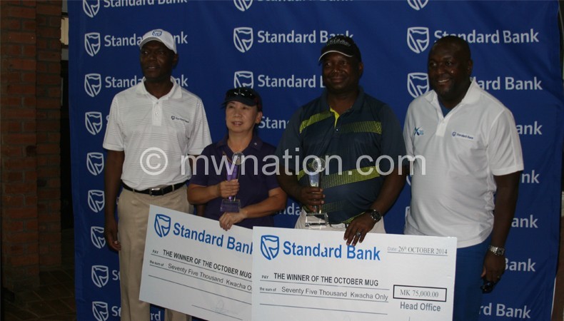 Odillo (2ndR) and Cho (L) display their dummy cheques as Standard Bank CEO Andrew Mashanda looks on