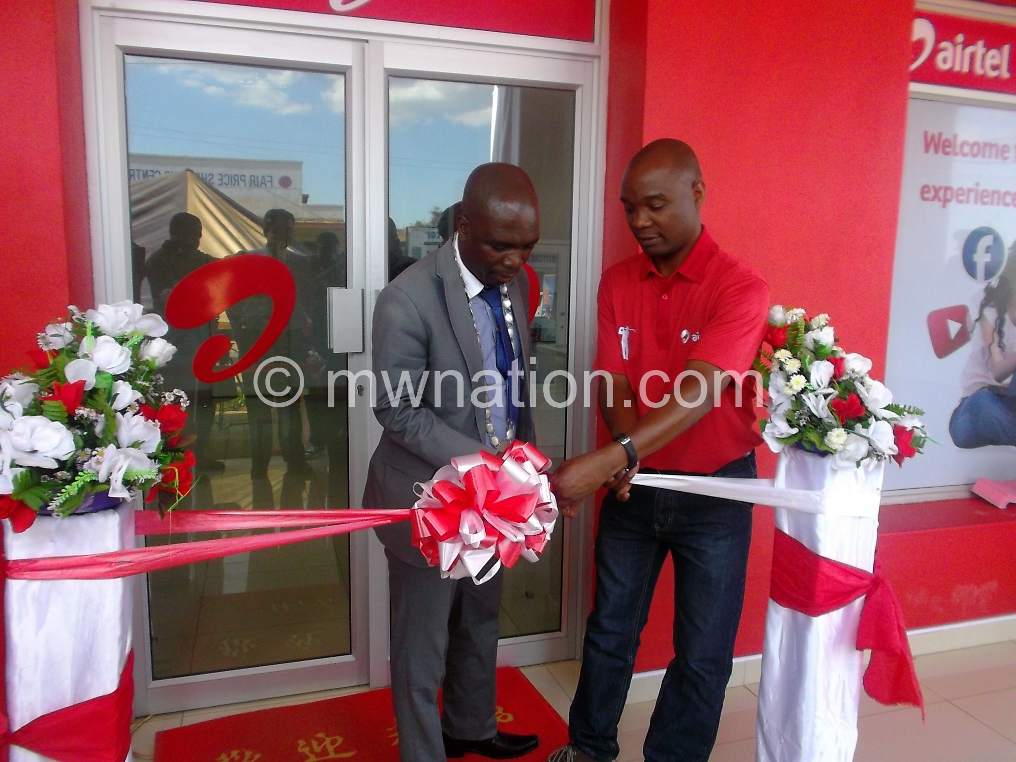 Maunde (L) cutting the ribbon assisted by Kamoto marking the opening of the new shop in Zomba