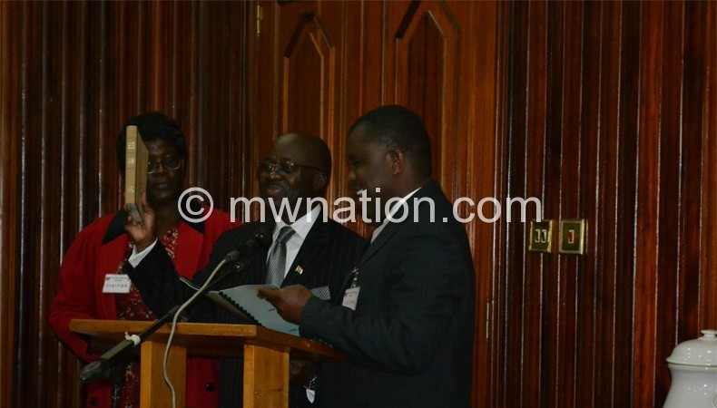 Nyirenda (holding Bible) flanked by his wife, being sworn in