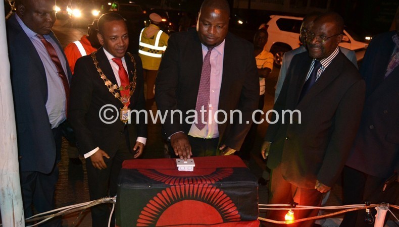 Nankhumwa switching on the lights as Chalamanda and other officials look on