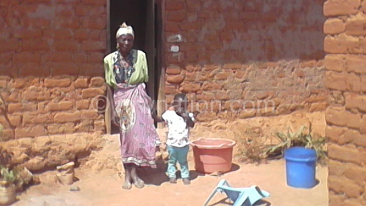 Nkhwazi with her great grandchild outside her home