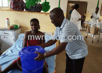 Chirwa(R)handing over a  plastic bucket to a patient