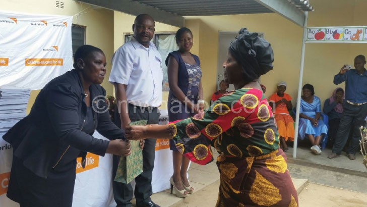 A caregiver (R) being awarded while Malisita (in white shirt) looks on