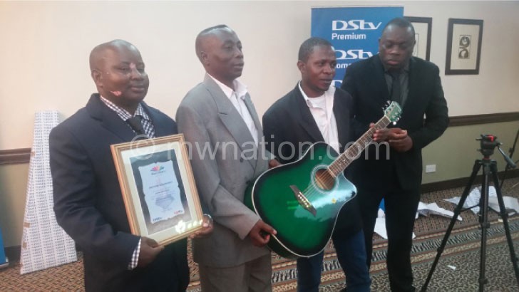 Nyirenda (R), Maliro (L) and two members of the band pose with the guitar and certificate