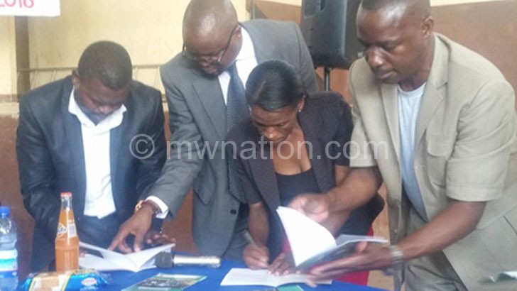 Kasunda (in spectacles) going through the charter with colleagues