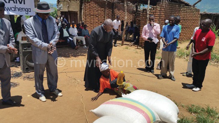 A beneficiary lies down on the ground in appreciation of the donation