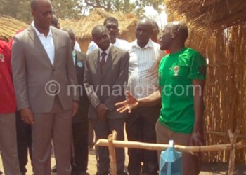 Muluzi (in grey suit) inspects a handwashing facility outside a toilet