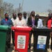 Officials pose in front of the bins