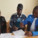 Chiona (C) is shown where to sign by Silver executive committee member 
Assedi Mgomba as Nyirenda (L) looks on