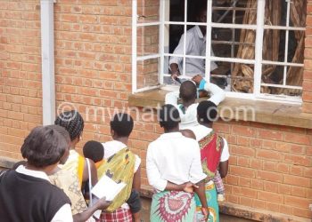 Patients queue to get medication from a pharmacy at a public hospital