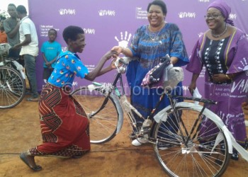 Chazama and Mihowa (R) presenting a bicycle to a beneficiary