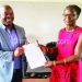 Mwenda (L) presents a copy of the endorsed rules to Mzengo